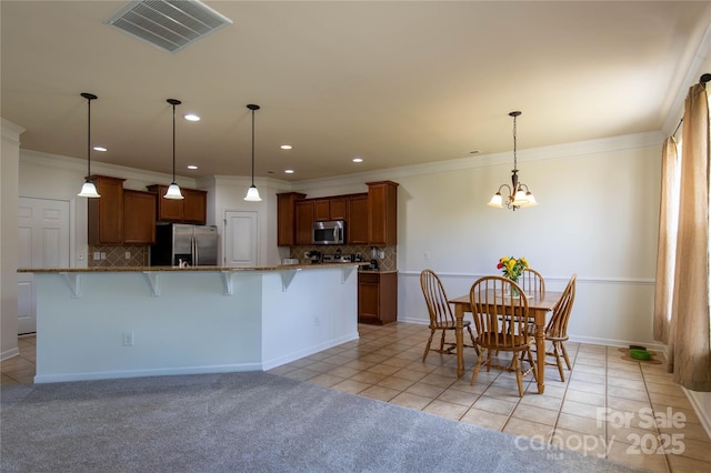 159 Saye Pl, Mooresville, NC 28115 - kitchen featuring appliances with stainless steel finishes, a kitchen bar, light tile patterned flooring, brown cabinets, and recessed lighting