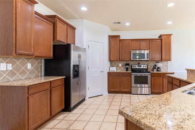 159 Saye Pl, Mooresville, NC 28115 - kitchen with stainless steel appliances, light tile patterned flooring, tasteful backsplash, brown cabinetry, and light stone countertops