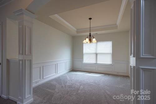 159 Saye Pl, Mooresville, NC 28115 - spare room featuring a decorative wall, a tray ceiling, a chandelier, decorative columns, and a wainscoted wall