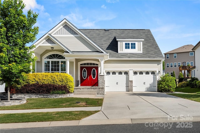 craftsman-style house with a garage, concrete driveway, board and batten siding, roof with shingles, and a front lawn