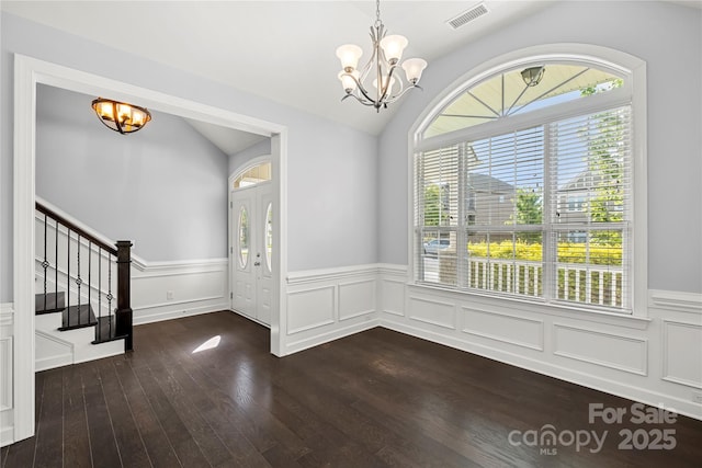 entrance foyer with a chandelier, dark wood-style floors, stairway, a wainscoted wall, and lofted ceiling