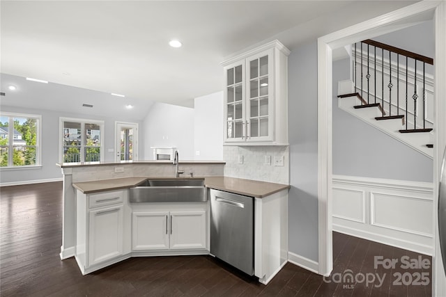 kitchen with dishwasher, a sink, tasteful backsplash, a peninsula, and dark wood-style flooring