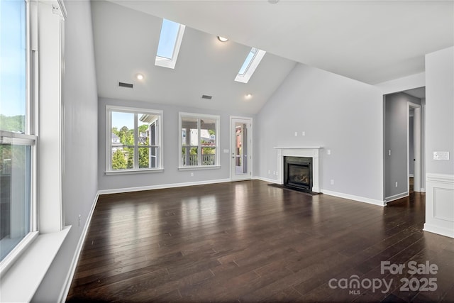 unfurnished living room featuring a skylight, a high end fireplace, dark wood-type flooring, and high vaulted ceiling