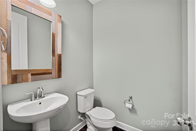 bathroom featuring a sink, baseboards, and toilet