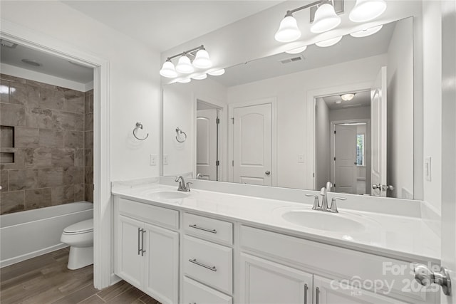 bathroom with double vanity, wood finished floors, toilet, and  shower combination