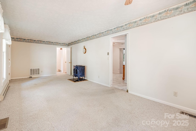 3127 Butler Bridge Rd, Mills River, NC 28759 - empty room with a wood stove, carpet flooring, baseboards, and a textured ceiling