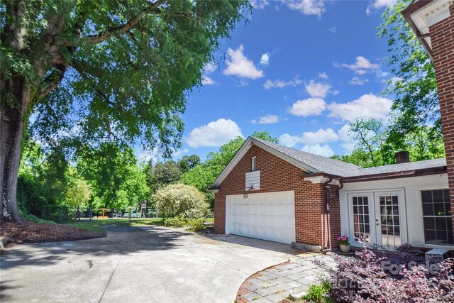 1101 Pee Dee Ave, Albemarle, NC 28001 - view of property exterior with french doors, driveway, an attached garage, brick siding, and a chimney