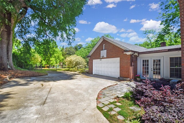 1101 Pee Dee Ave, Albemarle, NC 28001 - view of side of home featuring brick siding, concrete driveway, an attached garage, french doors, and a chimney