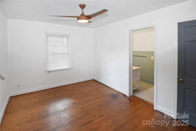 1101 Pee Dee Ave, Albemarle, NC 28001 - unfurnished bedroom featuring wood finished floors, baseboards, a ceiling fan, and ensuite bathroom