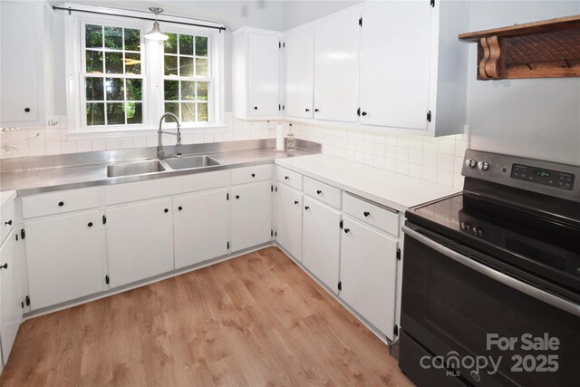 1101 Pee Dee Ave, Albemarle, NC 28001 - kitchen with electric range, a sink, white cabinetry, light wood-style flooring, and decorative backsplash