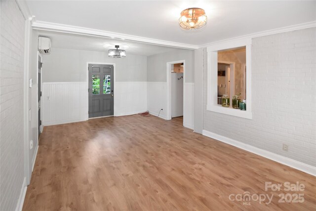 1101 Pee Dee Ave, Albemarle, NC 28001 - unfurnished room featuring wood finished floors, an AC wall unit, wainscoting, brick wall, and a chandelier