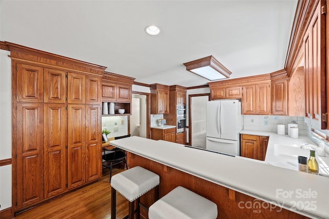 7103 Forest Ridge Rd, Matthews, NC 28104 - kitchen featuring freestanding refrigerator, a peninsula, tasteful backsplash, light countertops, and wood finished floors