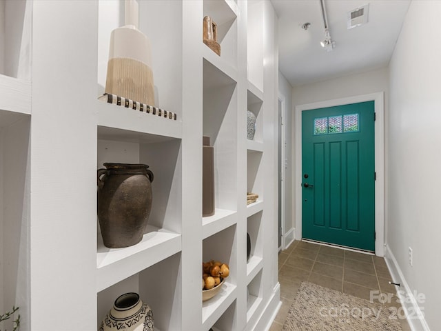 mudroom with rail lighting, tile patterned floors, and baseboards