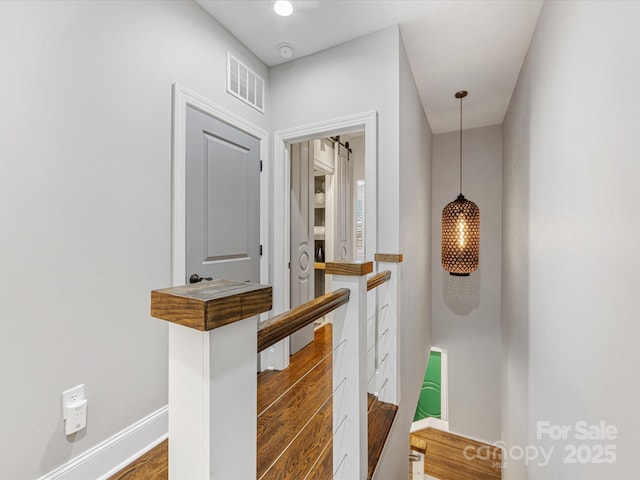 hallway featuring an upstairs landing, wood finished floors, and baseboards