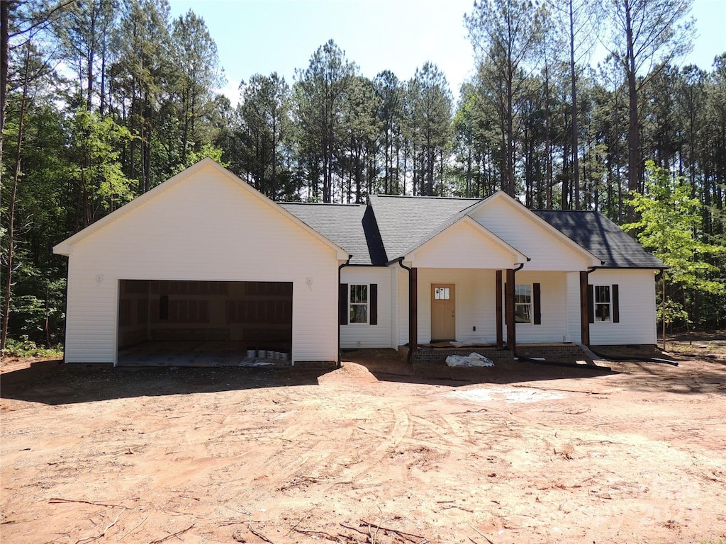 1761 Every Dr, Iron Station, NC 28080 - modern farmhouse style home with an attached garage, driveway, a porch, and view of scattered trees