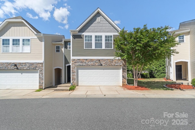 view of property featuring stone siding, a garage, and concrete driveway