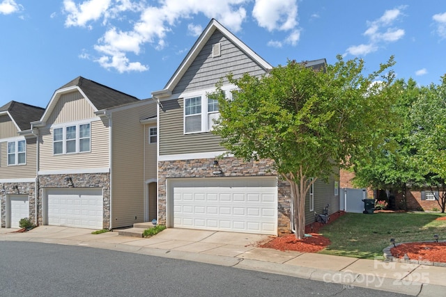 view of front of property with stone siding, a garage, concrete driveway, and a front yard