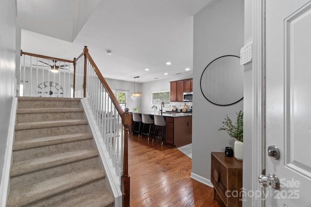 staircase featuring hardwood / wood-style flooring, recessed lighting, and baseboards