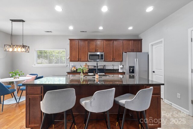 kitchen with stainless steel appliances, a sink, an island with sink, a kitchen breakfast bar, and recessed lighting