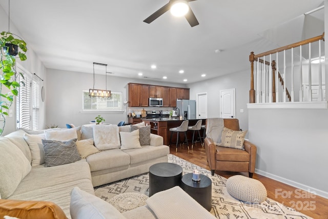 living room with wood finished floors, recessed lighting, ceiling fan, baseboards, and stairs