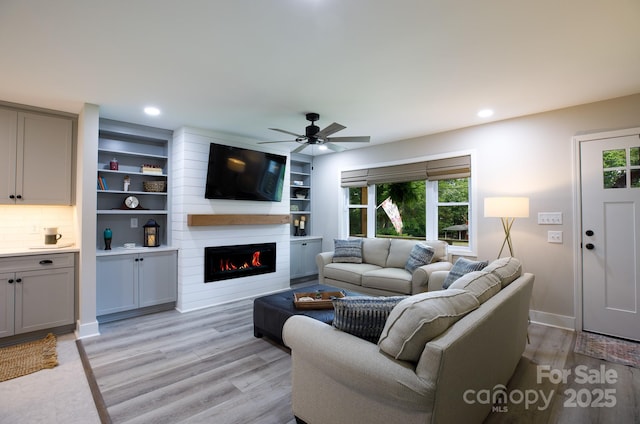 living area featuring a fireplace, a ceiling fan, plenty of natural light, and light wood-style floors