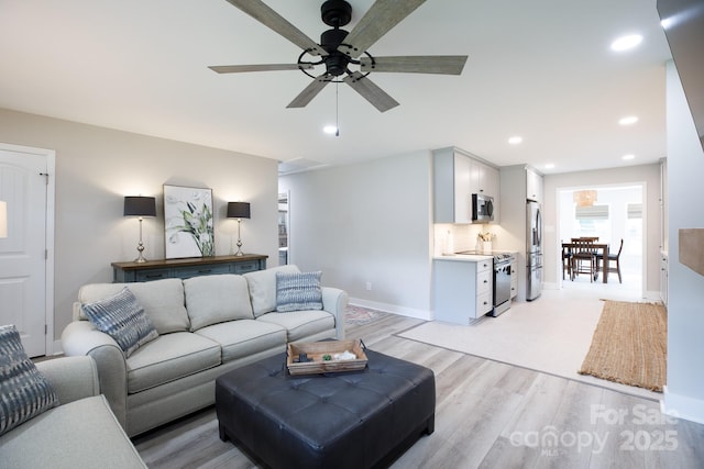 living area with light wood-style flooring, baseboards, ceiling fan, and recessed lighting
