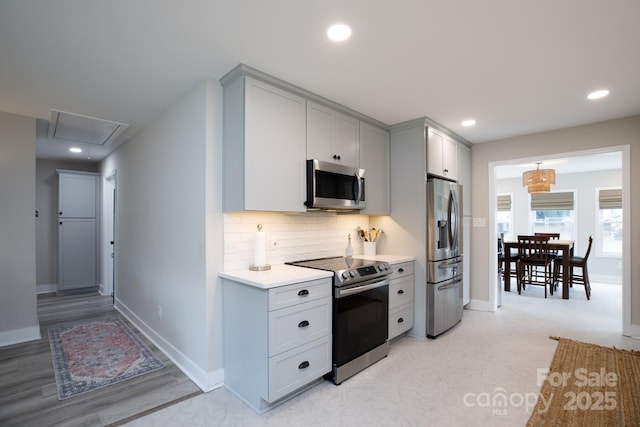 kitchen featuring baseboards, light countertops, stainless steel appliances, and gray cabinetry