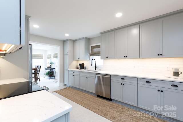 kitchen with backsplash, dishwasher, gray cabinets, and a sink