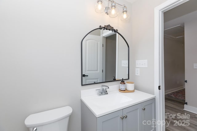 half bathroom featuring vanity, toilet, and wood finished floors