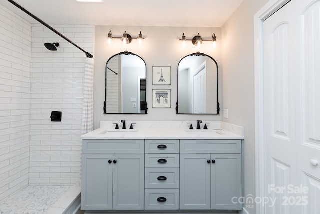 full bathroom with double vanity, a tile shower, and a sink