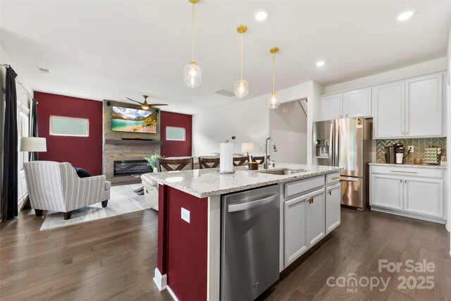 5727 Lavaux Ct, Charlotte, NC 28214 - kitchen with stainless steel appliances, a sink, a large fireplace, ceiling fan, and white cabinetry