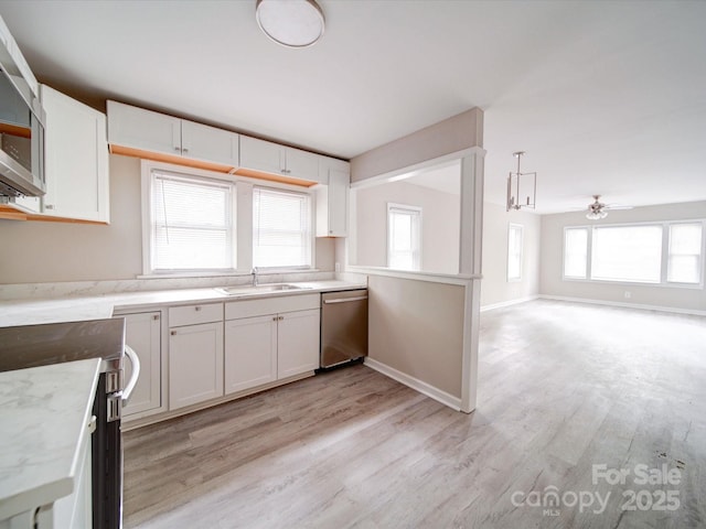 kitchen with stainless steel appliances, white cabinetry, light wood finished floors, a sink, and healthy amount of natural light