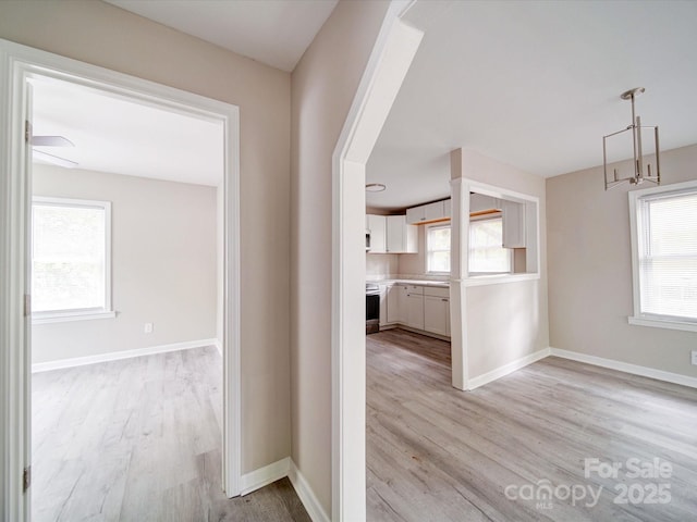 corridor with light wood-type flooring and baseboards