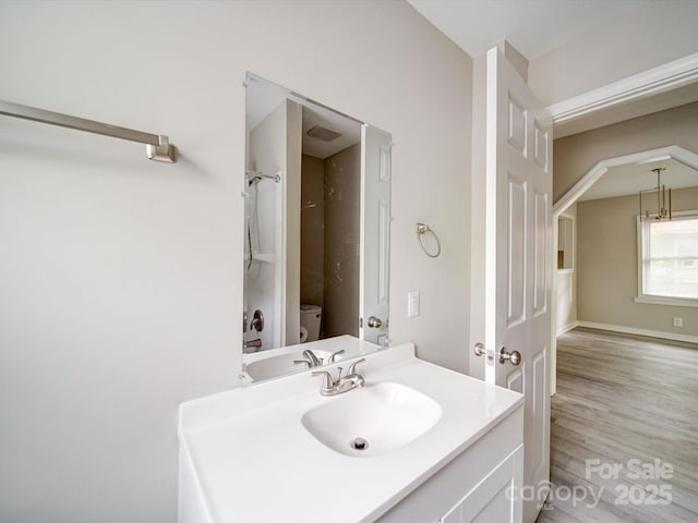 bathroom featuring toilet, wood finished floors, vanity, and a shower