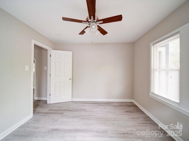 empty room featuring a ceiling fan, light wood finished floors, and baseboards