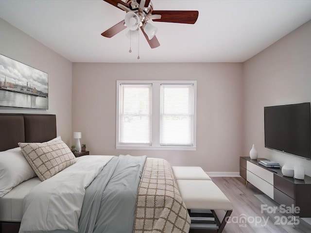 bedroom featuring light wood finished floors, a ceiling fan, and baseboards