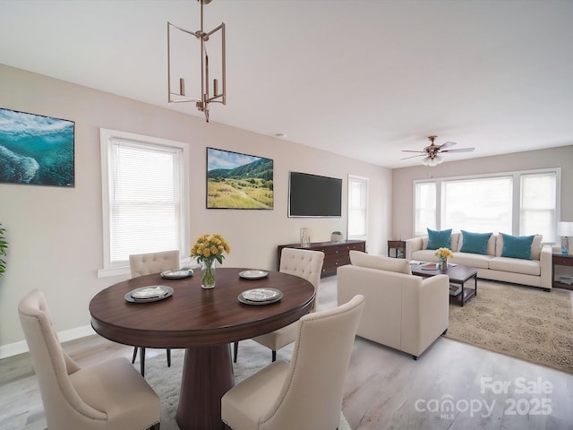 dining space with light wood-type flooring, healthy amount of natural light, ceiling fan, and baseboards