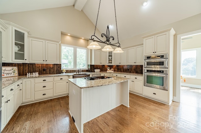 221 Stillwater Rd, Troutman, NC 28166 - kitchen featuring stainless steel double oven, beam ceiling, light wood-style flooring, a center island, and light stone counters