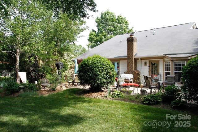 back of property featuring a patio, a yard, and a chimney