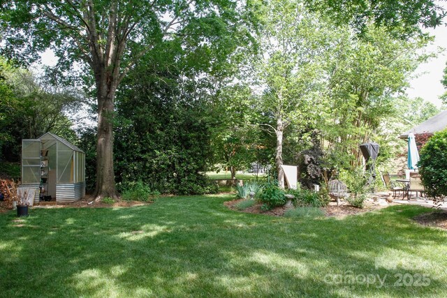 view of green lawn with an exterior structure