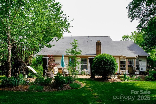 rear view of property featuring a yard, a patio area, and a chimney