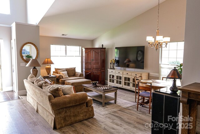 living area with a chandelier, lofted ceiling, wood finished floors, and baseboards