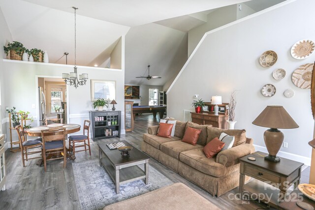 living room featuring plenty of natural light, wood finished floors, high vaulted ceiling, a chandelier, and ceiling fan