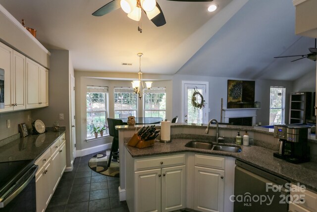 kitchen featuring a ceiling fan, a sink, appliances with stainless steel finishes, white cabinetry, and vaulted ceiling
