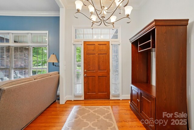 entrance foyer featuring a chandelier, light wood-type flooring, ornamental molding, and baseboards