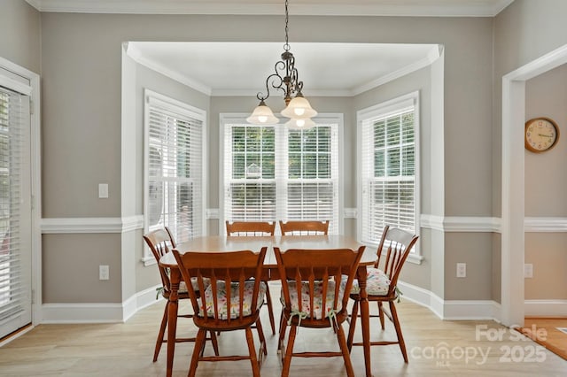 dining area featuring light wood-type flooring, a chandelier, baseboards, and ornamental molding