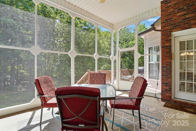 sunroom with plenty of natural light and view of wooded area