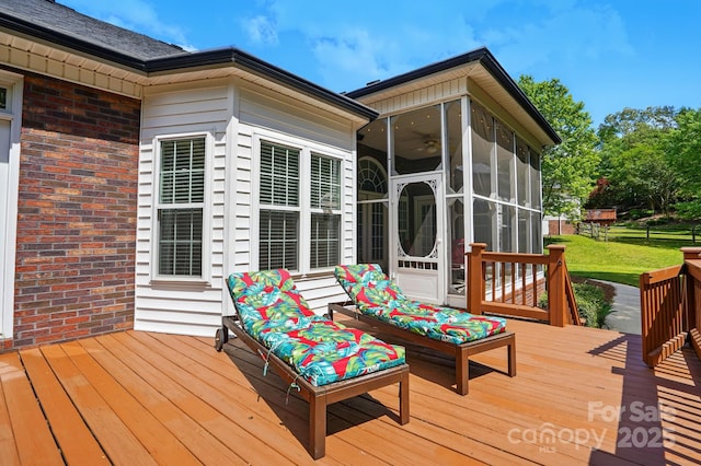 wooden deck with a sunroom and a lawn