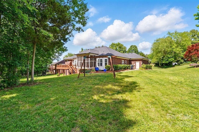 rear view of property with a deck, stairway, a yard, and an attached garage