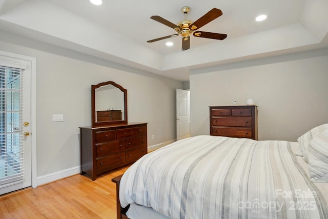 bedroom with a tray ceiling, light wood-type flooring, baseboards, recessed lighting, and ceiling fan